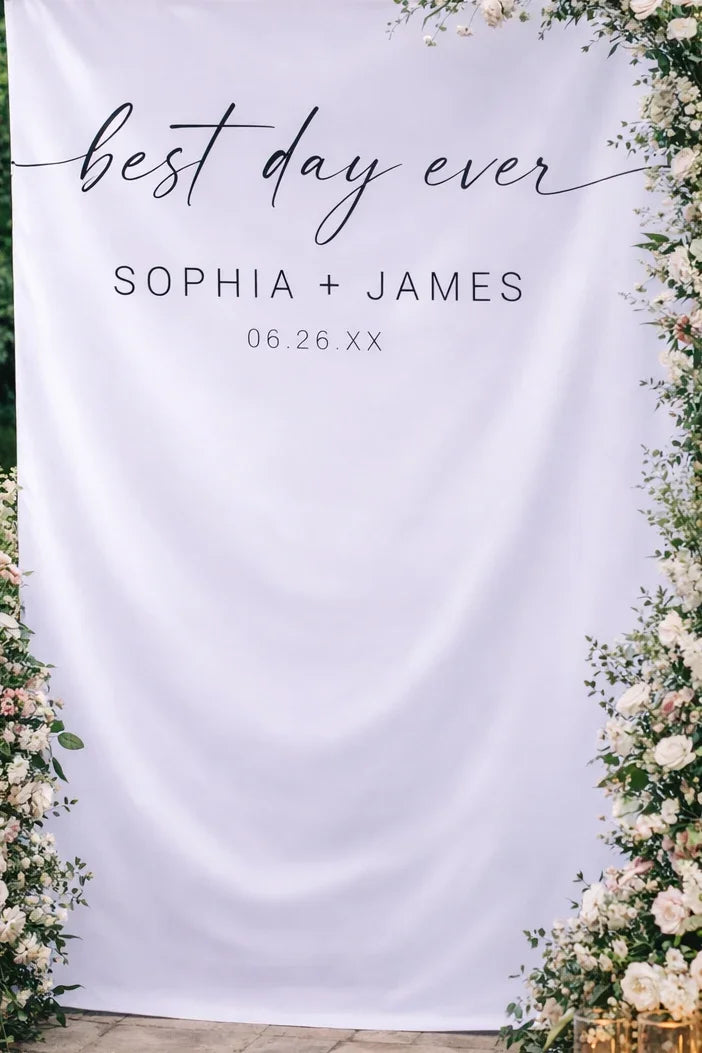 Wedding backdrop with 'best day ever' text and floral decorations.