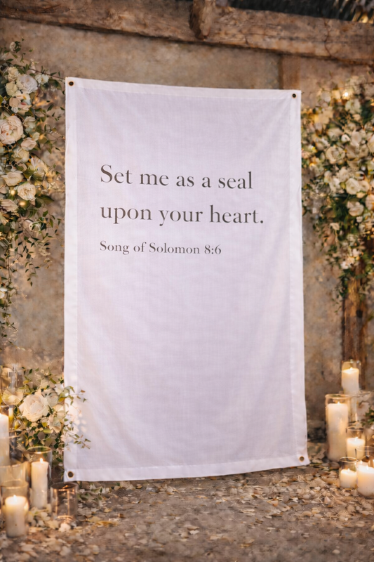 Decorative banner with text 'Set me as a seal upon your heart' in a romantic setting with flowers and candles.