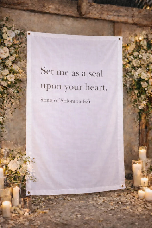 Decorative banner with text 'Set me as a seal upon your heart' in a romantic setting with flowers and candles.